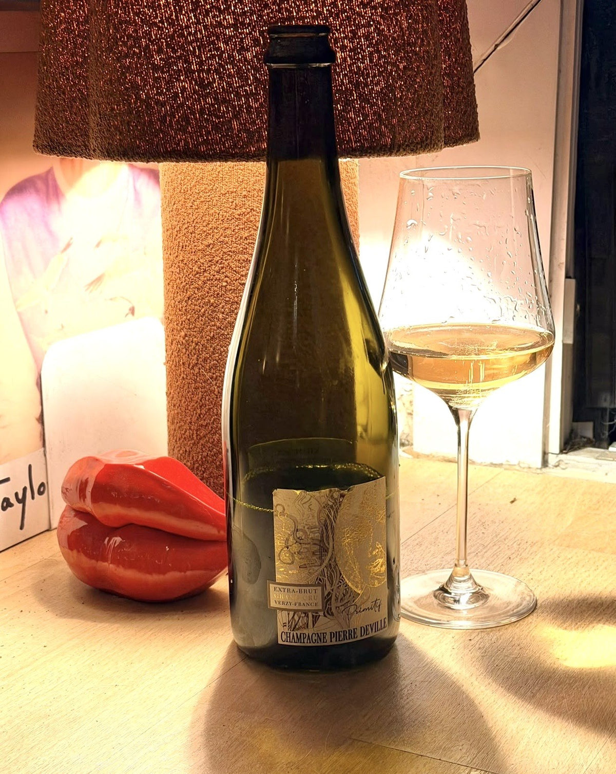Bottle of Champagne Pierre Deville Primitif Extra Brut from Verzy beside a glass of deep golden wine