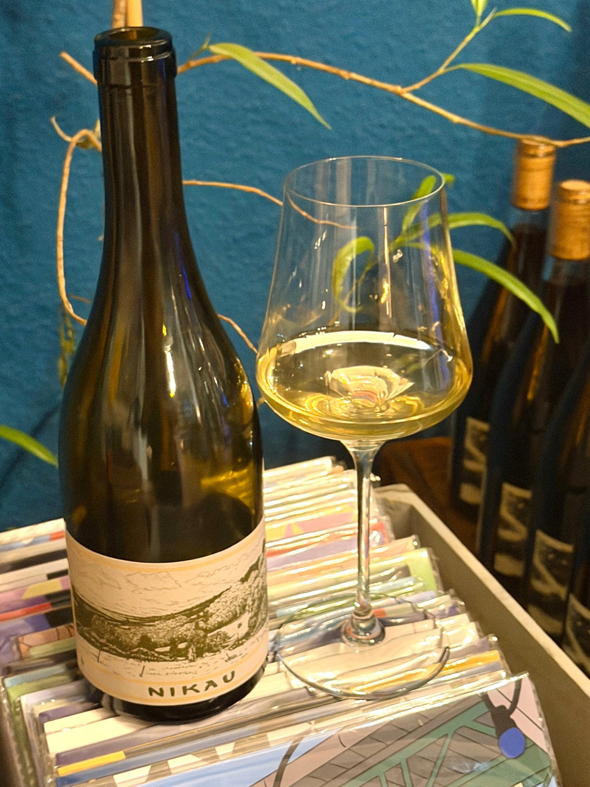 Bottle of Nikau from Gippsland with a glass of white wine against a blue wall